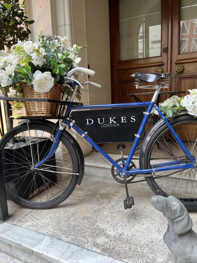 Dukes Bar London Mayfair Hotel, bicycle with potted flowers in front of Dukes bar sign