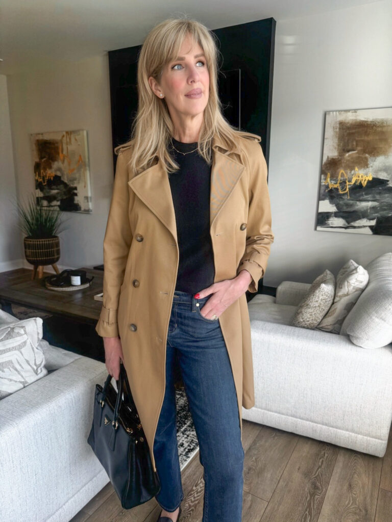 what to wear in paris this fall - Woman wearing a classic camel trench coat styled with dark denim, black top, and black handbag