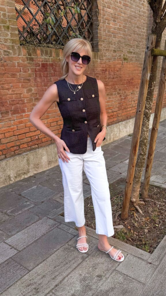 Chic sleeveless black buttoned top with white pants and sandals — summer outfits for women over 40, French fashion style inspiration, and what to wear